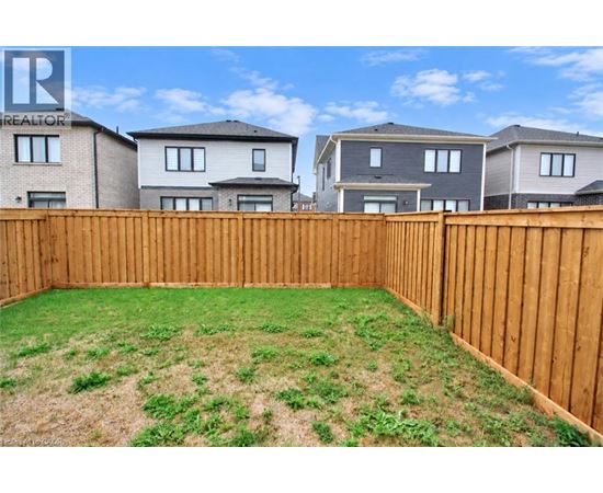 A backyard with a wooden fence and a grassy area.