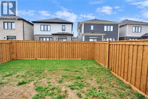 A backyard with a wooden fence and a grassy area.