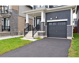 A house with a black garage door and a stone wall.
