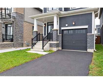 A house with a black garage door and a stone wall.