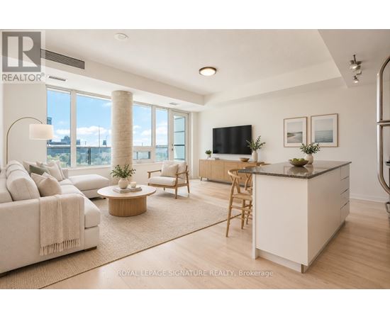 A well-lit, spacious living room with a large window, a sofa, a coffee table, and a kitchen area.
