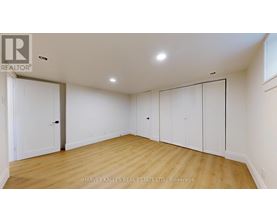 A spacious room with wooden floors and white walls, featuring a set of white doors.
