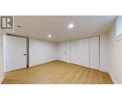 A spacious room with wooden floors and white walls, featuring a set of white doors.