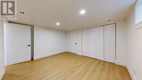 A spacious room with wooden floors and white walls, featuring a set of white doors.