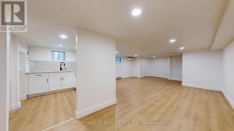 A spacious room with wooden flooring and white walls, with a cabinet and a window.