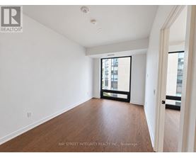A spacious room with wooden floors and a large window.
