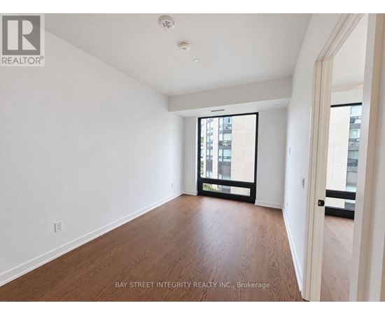 A spacious room with wooden floors and a large window.