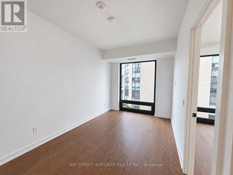 A spacious room with wooden floors and a large window.