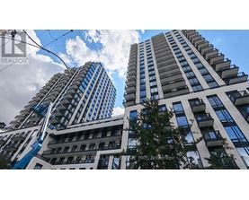 Two tall buildings with balconies and a blue sky with clouds in the background.