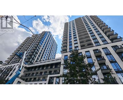 Two tall buildings with balconies and a blue sky with clouds in the background.