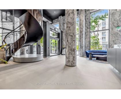 A modern office lobby with a spiral staircase and marble columns.