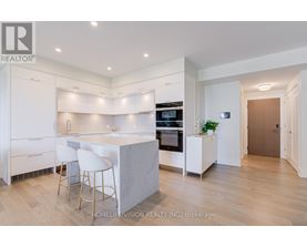 A modern kitchen with white cabinets and a marble island.