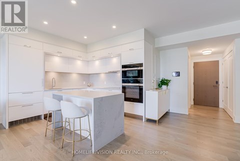 A modern kitchen with white cabinets and a marble island.