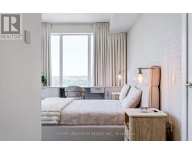 A bedroom with a large bed and a window overlooking the ocean.