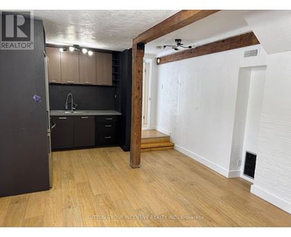 A kitchen with a refrigerator, sink, and cabinets.