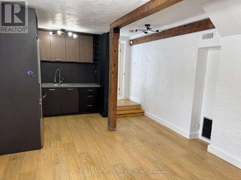 A kitchen with a refrigerator, sink, and cabinets.