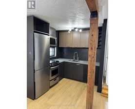 A kitchen with a refrigerator, oven, and sink.