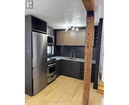A kitchen with a refrigerator, oven, and sink.