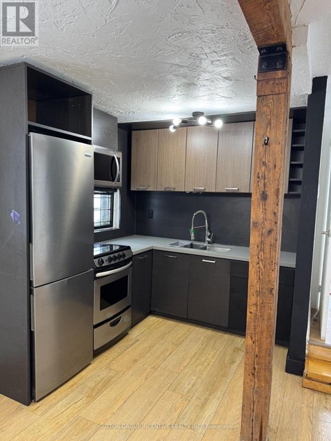 A kitchen with a refrigerator, oven, and sink.