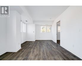 A spacious room with wooden flooring and white walls.