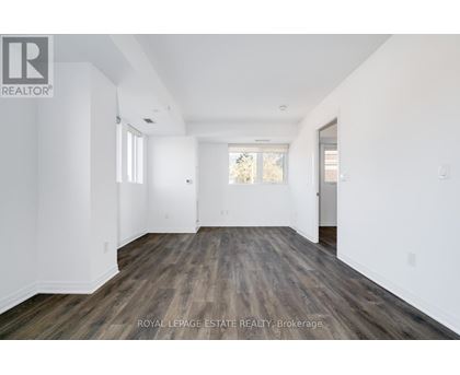 A spacious room with wooden flooring and white walls.