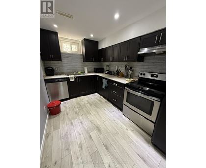 A modern kitchen with black cabinets and a wooden floor.