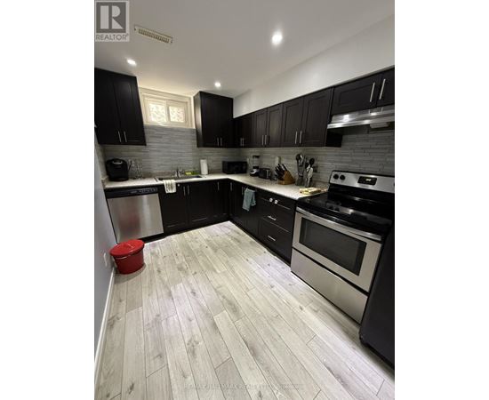 A modern kitchen with black cabinets and a wooden floor.