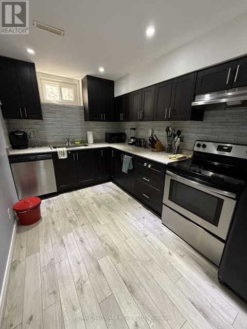 A modern kitchen with black cabinets and a wooden floor.