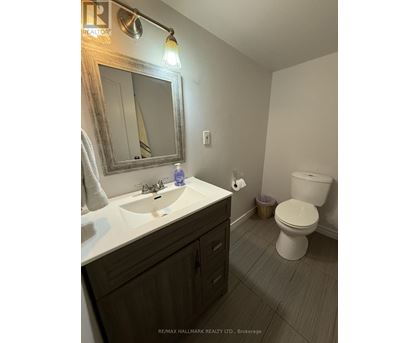 A bathroom with a toilet, sink, and mirror.