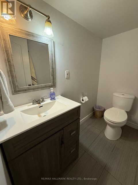 A bathroom with a toilet, sink, and mirror.