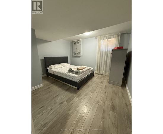 A bedroom with a bed, wooden floors, and a window with curtains.