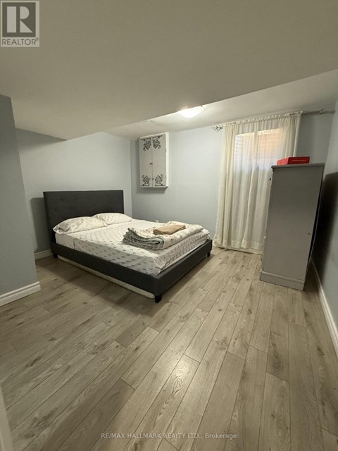 A bedroom with a bed, wooden floors, and a window with curtains.