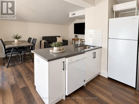A modern kitchen with white cabinets and a wooden floor.