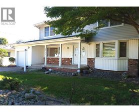 A house with a white front porch and a tree in front.