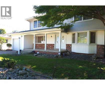 A house with a white front porch and a tree in front.