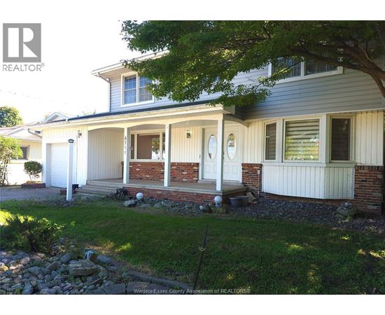 A house with a white front porch and a tree in front.
