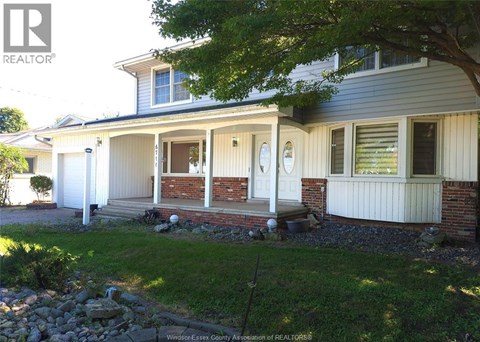 A house with a white front porch and a tree in front.