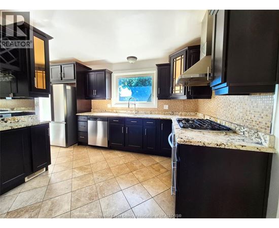 A kitchen with black cabinets and a tiled floor.