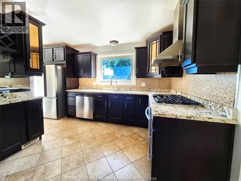 A kitchen with black cabinets and a tiled floor.