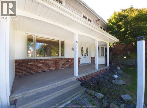 A house with a white porch and a brick wall.