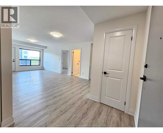 A spacious room with wooden flooring and white walls.