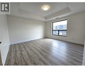 A spacious room with a large window and wooden flooring.