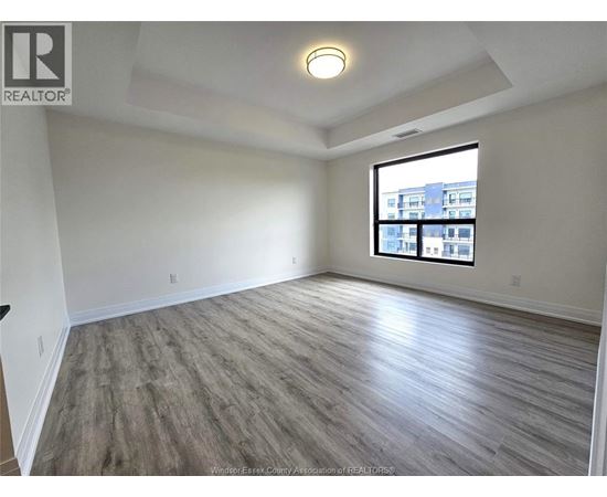 A spacious room with a large window and wooden flooring.
