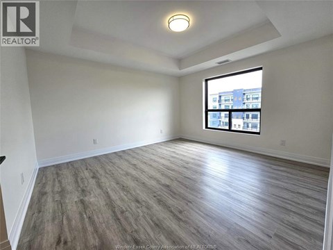 A spacious room with a large window and wooden flooring.