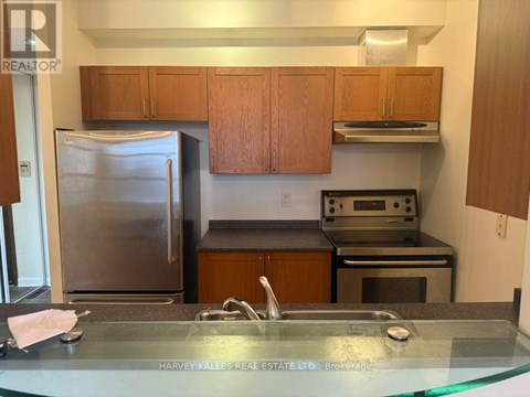 A kitchen with a refrigerator, oven, and cabinets.