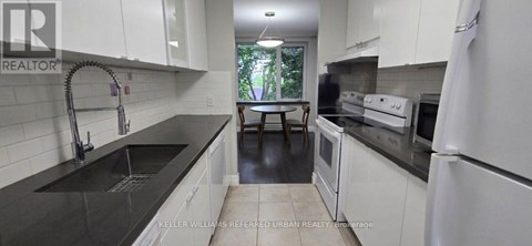 A kitchen with white cabinets and black countertops.