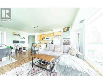 A living room with a couch, coffee table, and kitchen area in the background.