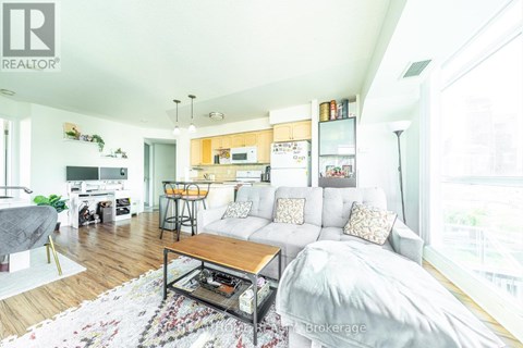 A living room with a couch, coffee table, and kitchen area in the background.