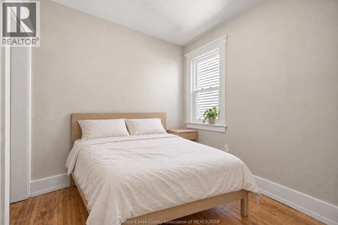 A bedroom with a bed, pillows, and a window with blinds.