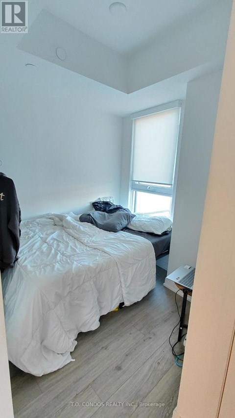 A bedroom with a bed, a window, and a nightstand.